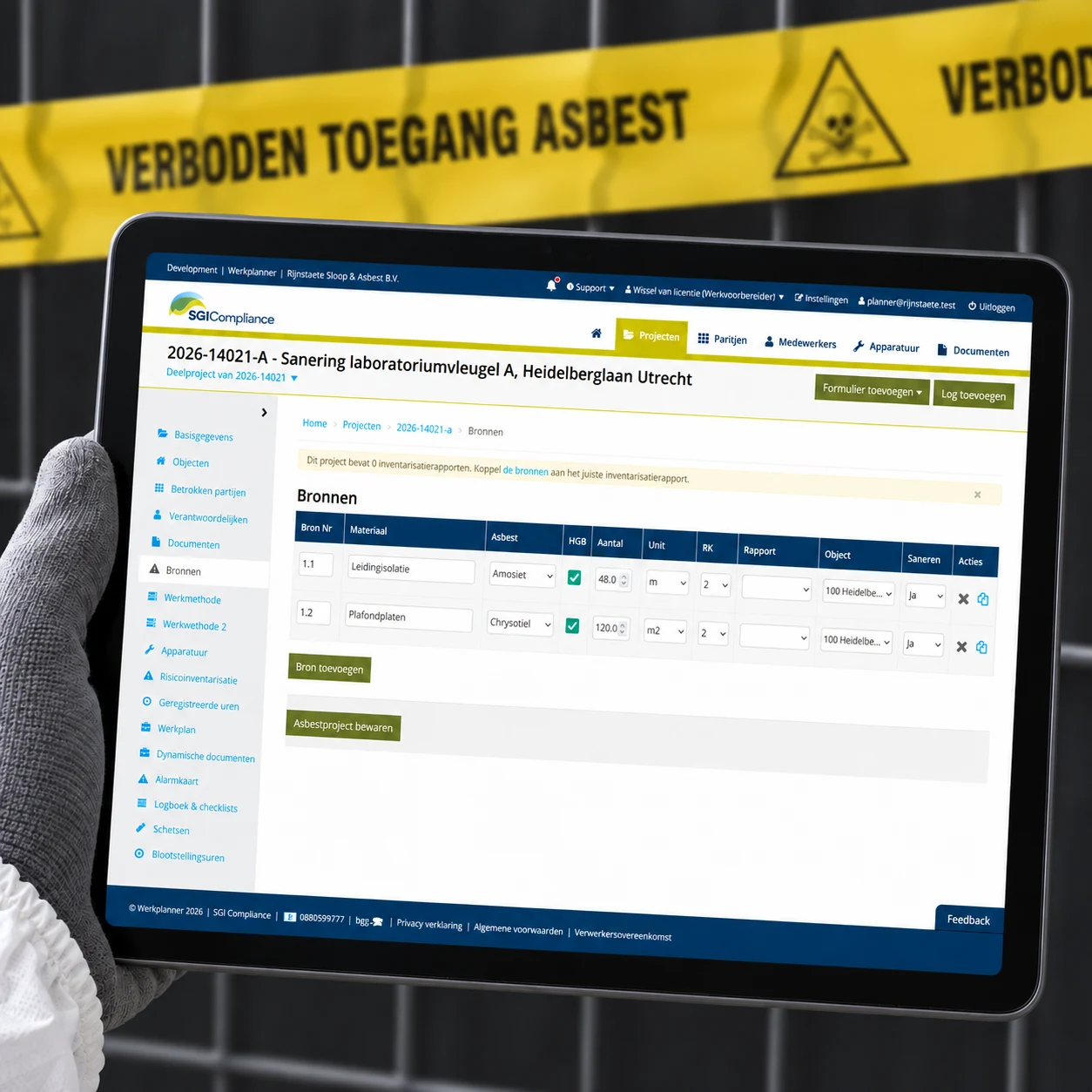 Tablet met de bronnen van een saneringsproject in Werkplanner, met een beschermende handschoen en asbestafzetlint op de achtergrond